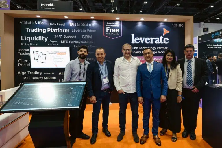 Six people stand in front of a Leverate booth at a trade show, with promotional banners and a touchscreen display visible in the background.