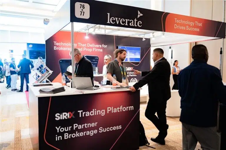 People interact at a booth for Leverate's Sirix Trading Platform at a business expo, with promotional banners and computers visible on the counter.